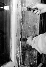 After removing paint from the seam between the interior stop and the jamb, the stop can be pried out and gradually worked loose using a pair of putty knives as shown.