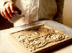 Colored slip, or liquid clay, is being poured into the indented portion of a reproduction encaustic tile, to create the pattern. Photo: H & R Johnson Tiles.